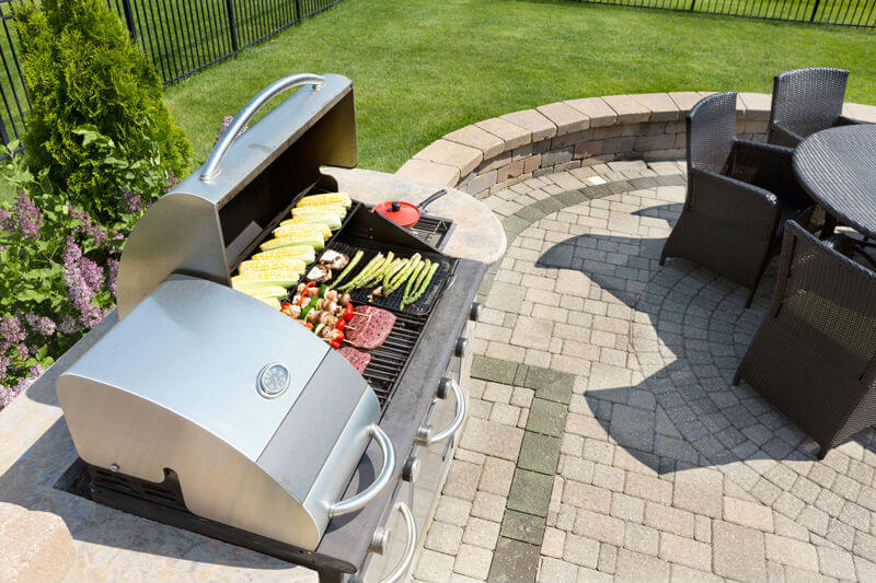 Photo of paved patio with a grill and table set